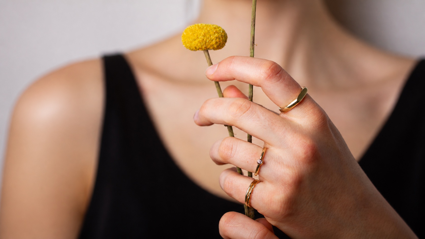 Goldringe an einer Hand mit gelber Blüte für SchmuckGraefin