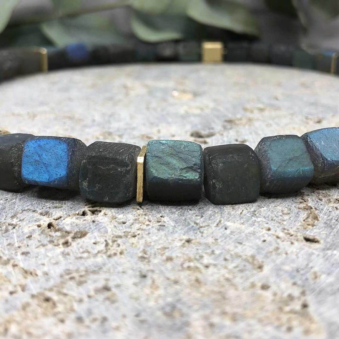 Armband mit schwarzen und blauen Steinen sowie goldenen Akzenten.
